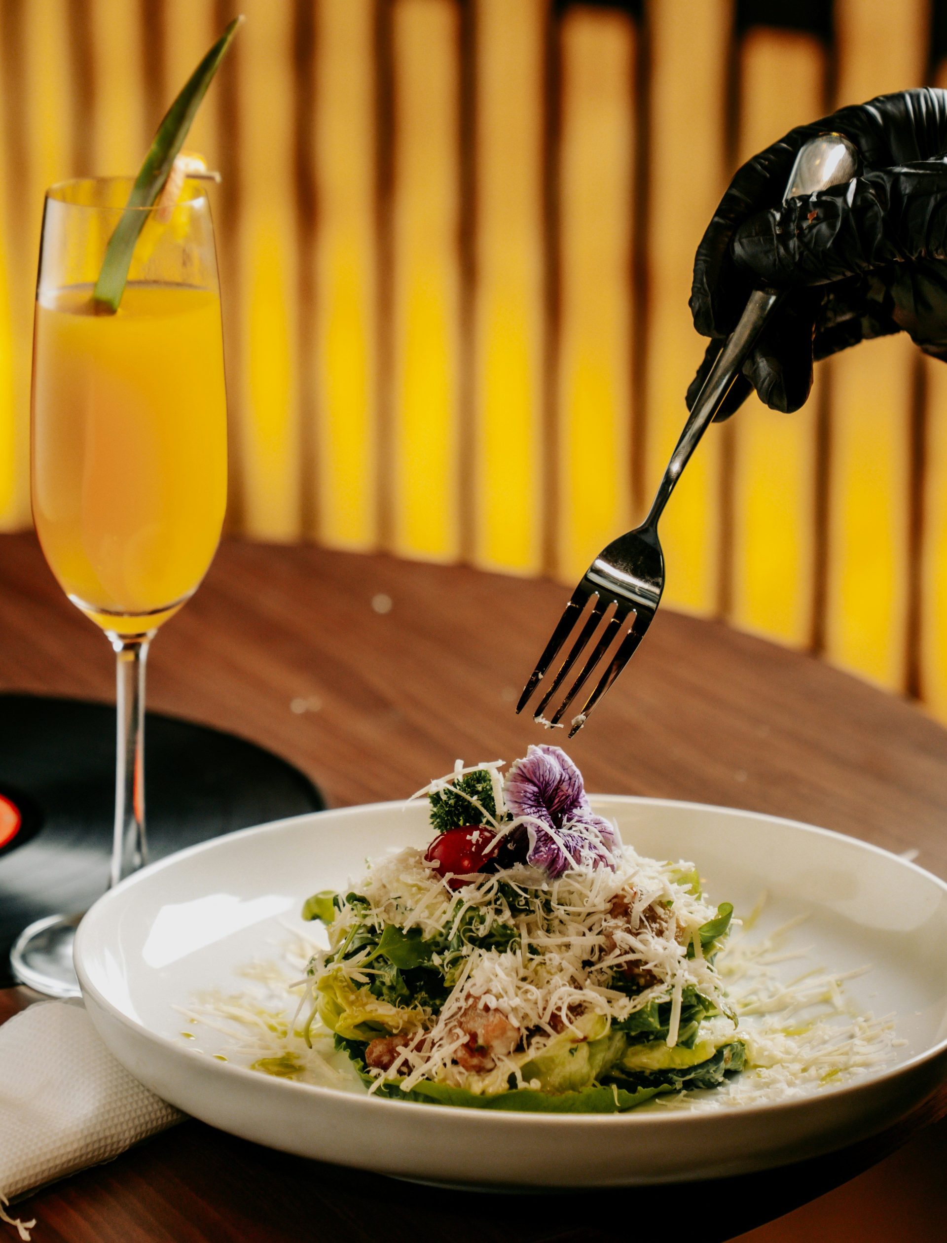A hand with a fork approaches a salad.